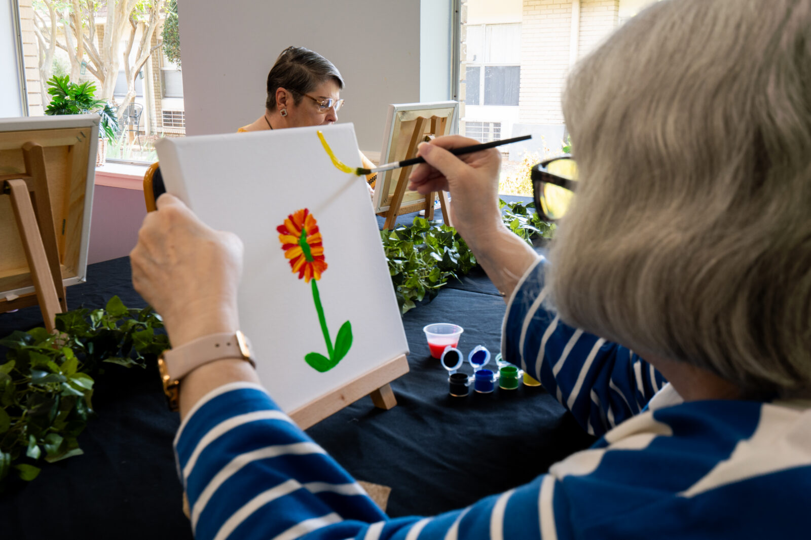 Senior resident painting a flower during a creative activity at a Diversicare care center.